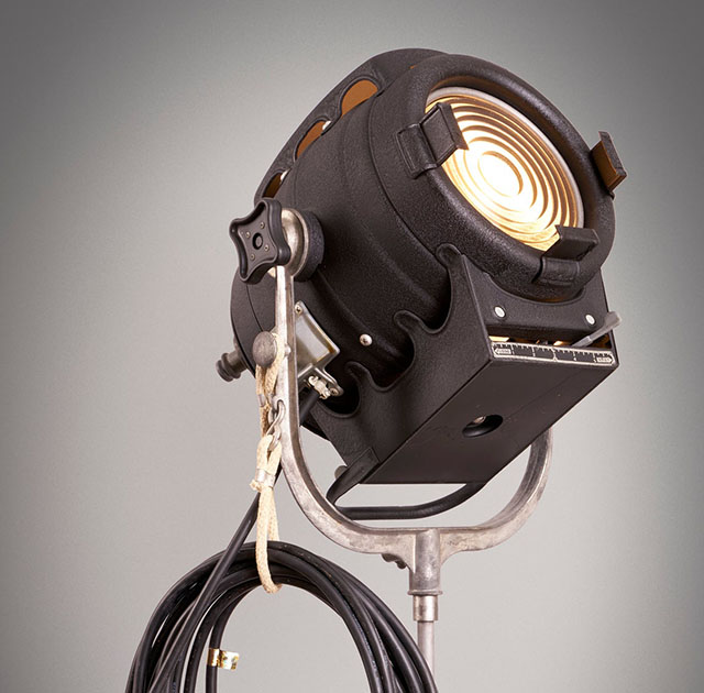 A fresnel lamp is a spotlight with a flass in front to spread/center the light. Here's a 1950's Bardwell & McAlister movie lamp, though it is still a lamp type in production and use.