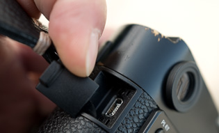 USB port

The Leica M9 has a small port for USB hidden behind a plastic cover. The sole purpose is if you want to use a cable to download images from the camera to the computer. It serves no other purpose or function. 

In later model Leica M 240 and so on there is no USB port anymore. 