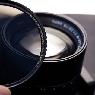 E67 filter thread  The front of the lens says E67, which is the Leica designation for 67mm filters.  For a 1.25 lens one should get a 3-stop Neutral Density filter (ND-filter), which works like "sunglasses" for the lens so you can use it in sunshine.  A 3-stop ND-filter reduces the light going through the lens 3 stops, so wide open at f/1.25 it will take light in as if of f/3.4 but remains the narrow depth of field of f/1.25. I recommend "X4-ND" 3-stop filters from Breakthrough Photography.  The manual specifically says the 75mm Noctilux is optimized for f/1.25 and using the aperture to stop down should only be done for depth of field control. 