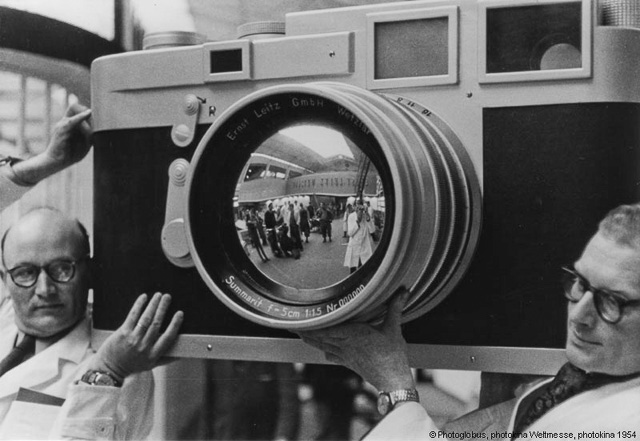 From the worlds biggest photo fair, the Photokina 1954 where two employees from Ernst Leitz Wetzlar (Leica Camera AG) carries a wooden marketing replica of what is to become the mother of all future Leica rangefinder models, the Leica M3. © 1954 Photoglobus.