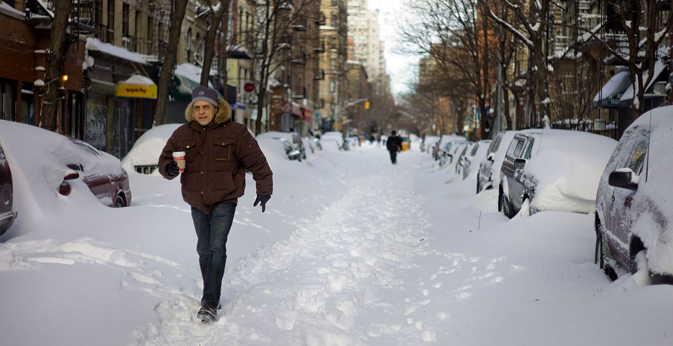 A new yorker walks with his coffee to go through 11th Street on Manhattan the morning after the snowstorm on December 26, 2010.