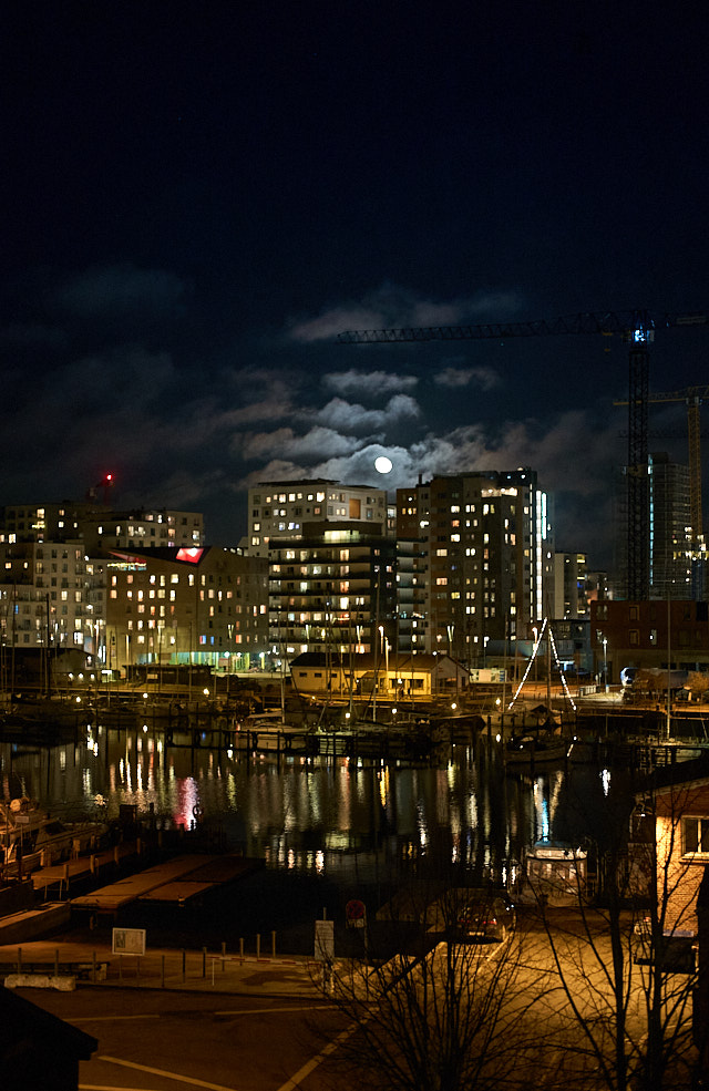 Moon over the new city on the harbor in Aarhus, Denmark. As seen from inside a warm apartment on a cold night. 3200 ISO. Leica 50mm Summilux-M ASPH f/1.4 BC. © Thorsten Overgaard.