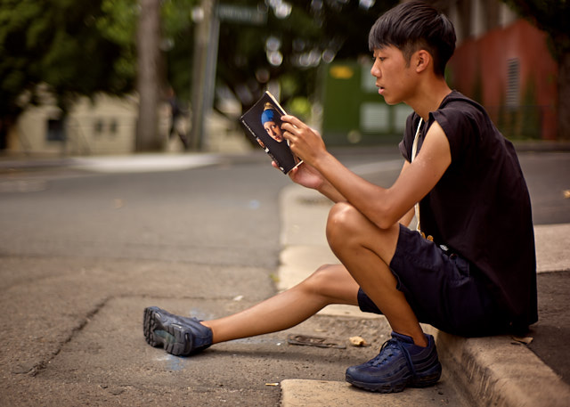 A boy reading "Girl with Pearl Earring" on the street in Sydney. He didn't know who Johannse Vermeer was, but now he does. It's all about the light. Leica M10-P with 7artisans 50mm f/1.1. © Thorsten Overgaard. 