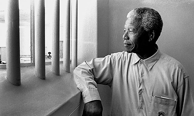 German born, living in South Africa, Jürgen Schadeberg (1931-2020) took this photograph of Nelson Mandela in his former cell at Robben Island. 